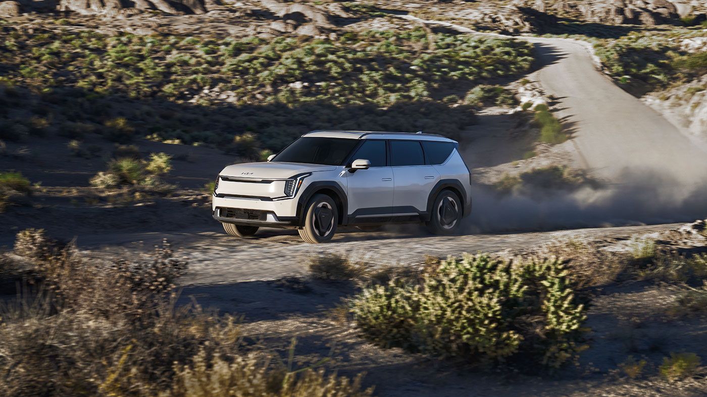 Vue latérale de la KIa EV9 sur route de sable en pleine puissance