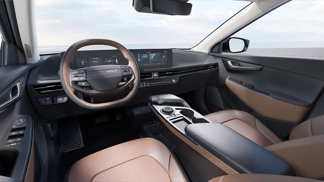Intérieur de la Kia EV6 2025 avec habitacle spacieux et volant à méplat et double écran numérique.