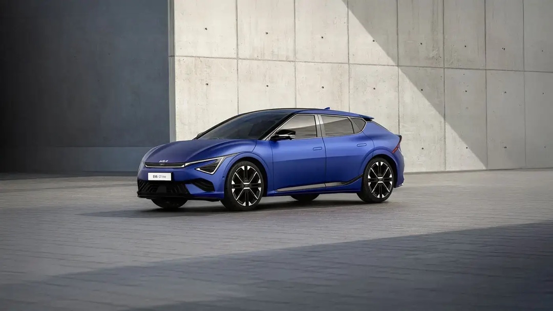 Kia EV6 en bleu mat, stationnée devant un mur en béton moderne, soulignant ses lignes futuristes et son design aérodynamique.
